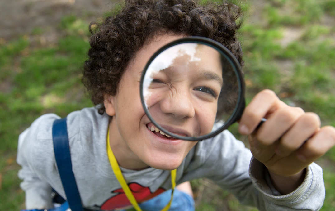 A child looks through a magnifying glass