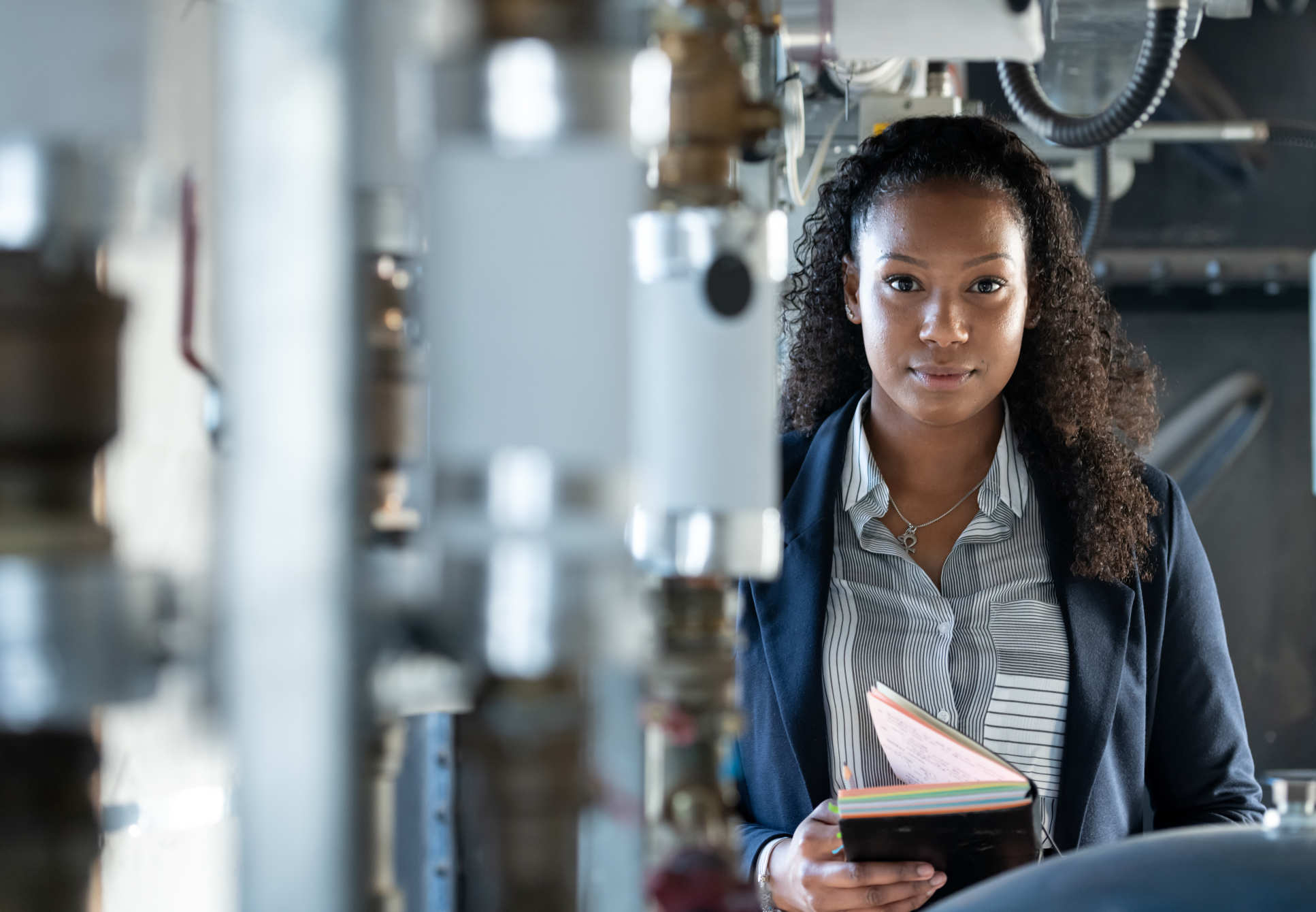 woman holding notebook standing among equipement