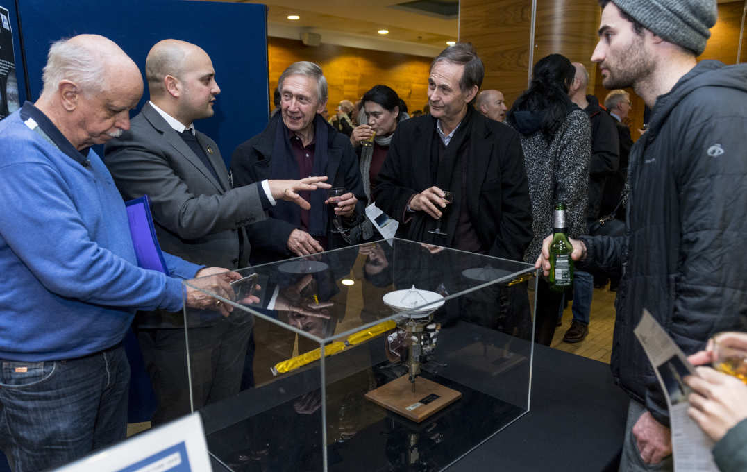 People talk over a model of the Cassini spacecraft