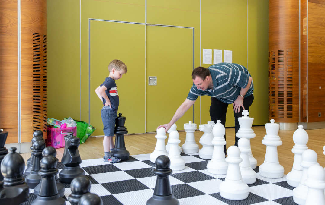 A boy and a man play giant chess together at the annual Bring Your Child To Work Day