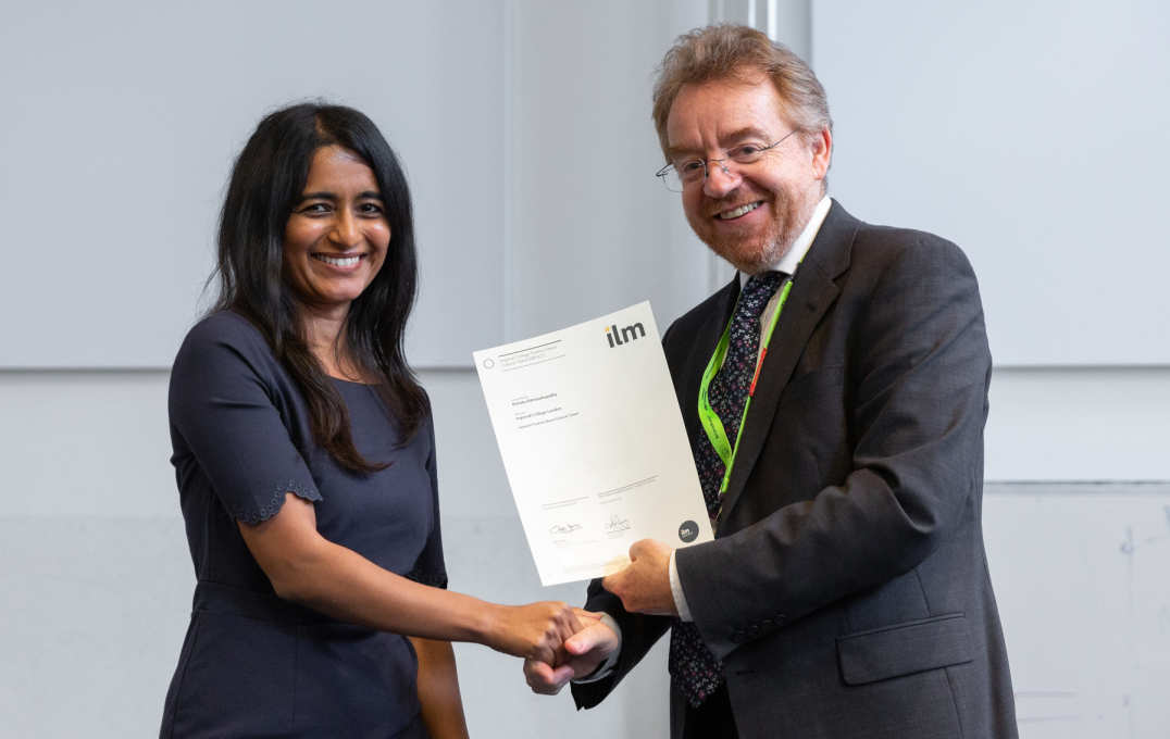 woman collects certificate and shakes man's hand