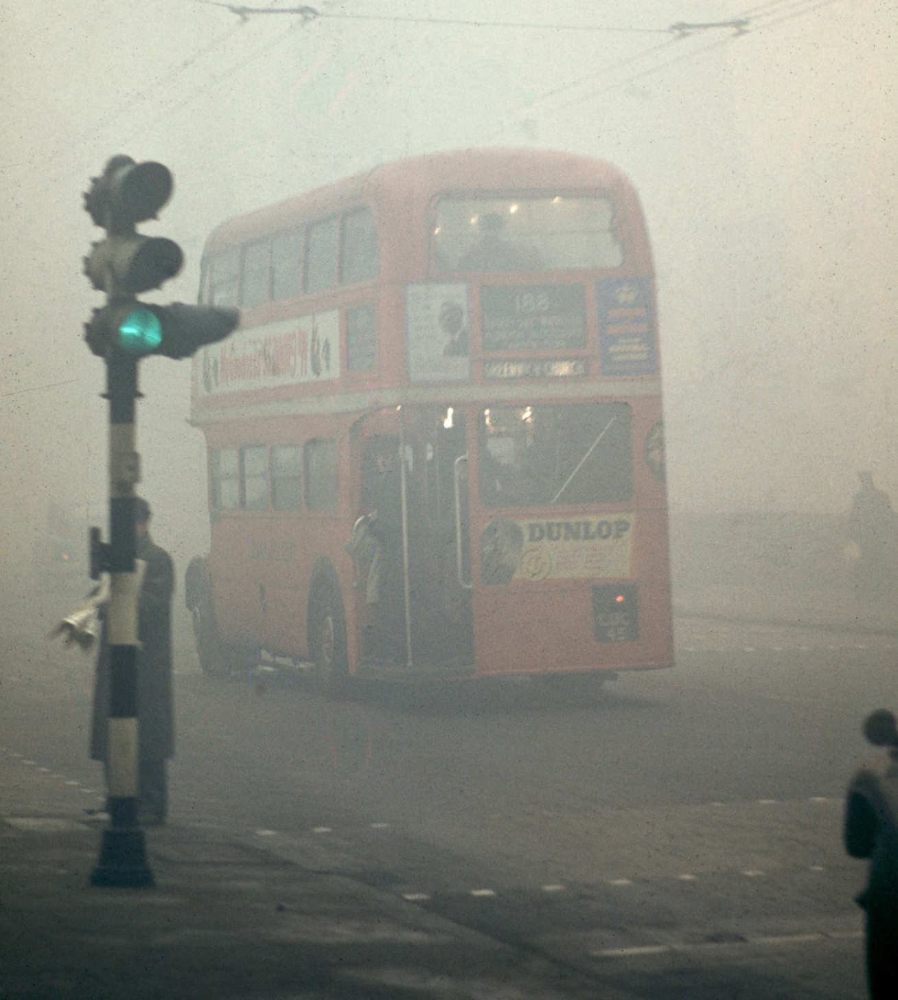 Photo depicts the back of a bus driving through a London smog in 1952