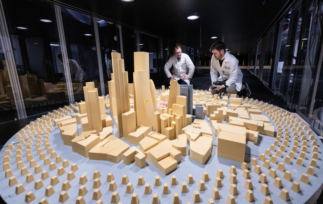 Photo of researchers looking over some models of buildings in the wind tunnel