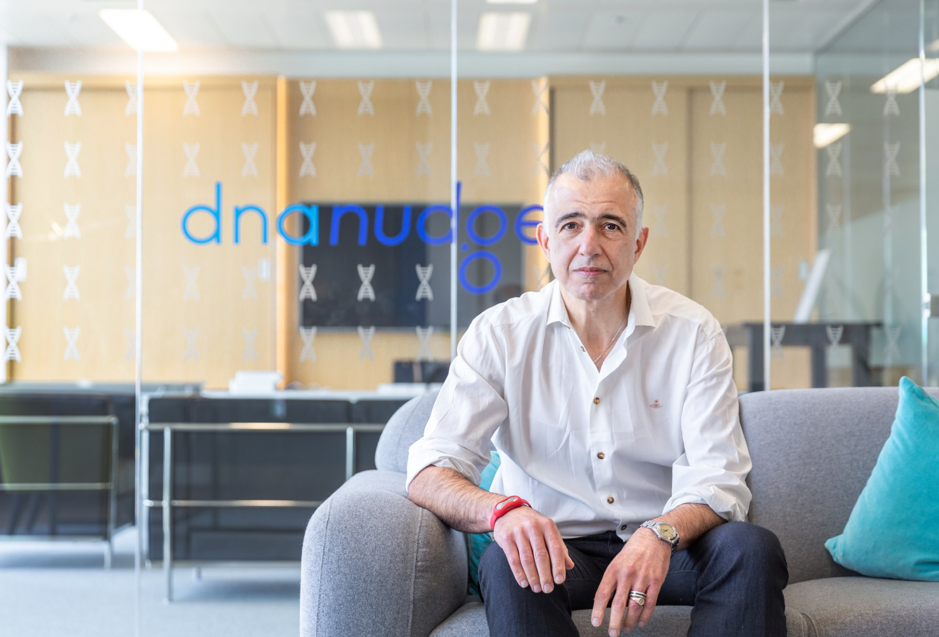 Man sitting in front of a glass background with DnaNudge logo