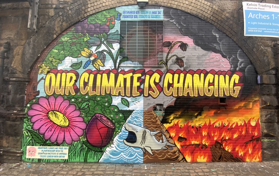 Raging wildfires contrasted with a sea and landscape featuring dragonflies, a bluebell (pressurised by invasive species) and the basking shark (at risk from illegal hunting, boat strikes and bycatch) with the slogan ‘Our Climate is Changing’. 