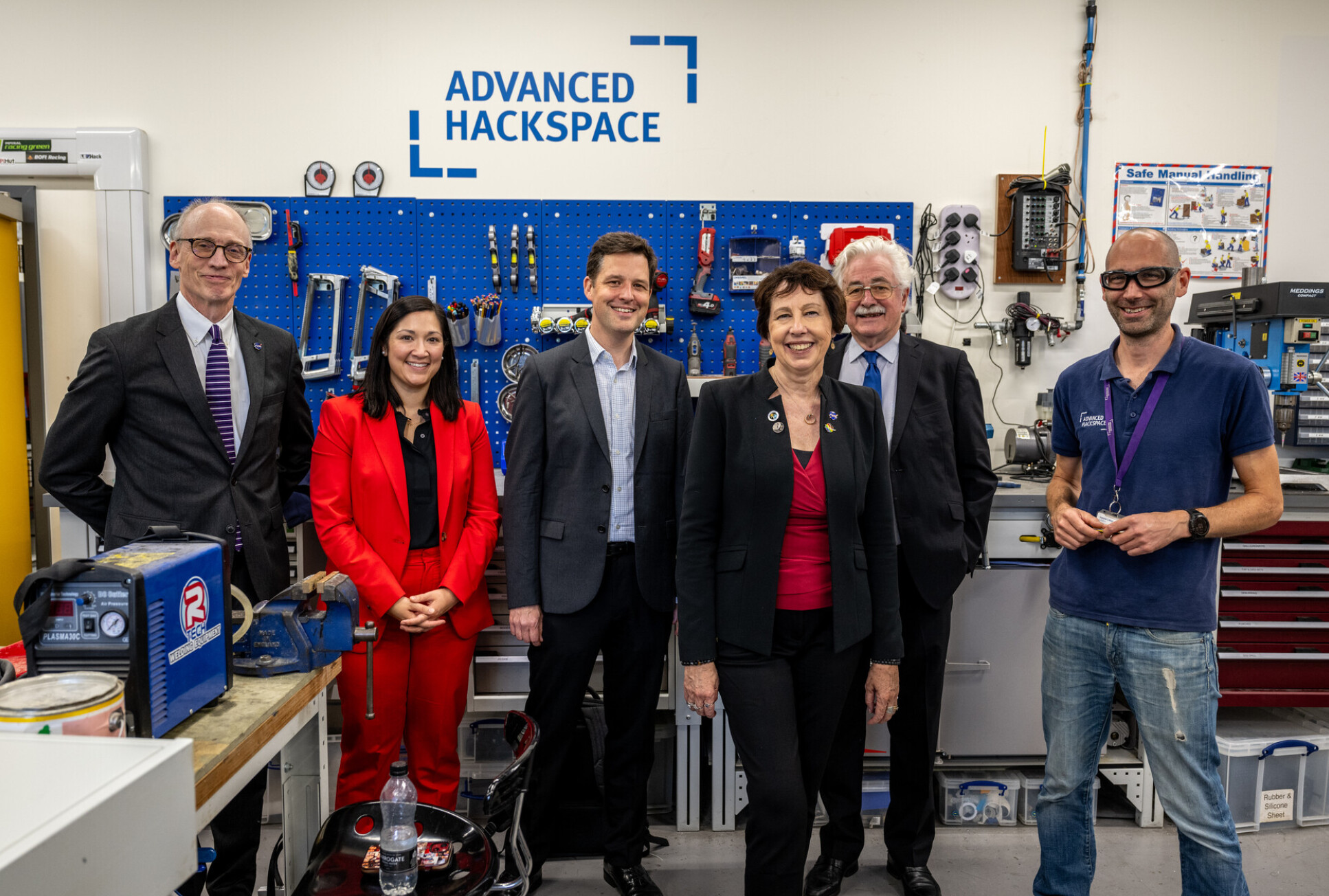 Group of people in a tool room with 'Advanced Hackspace' on the wall