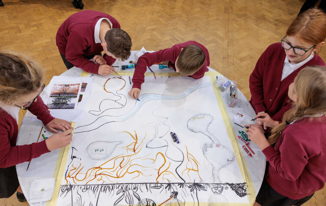 Children stood round a table making artwork