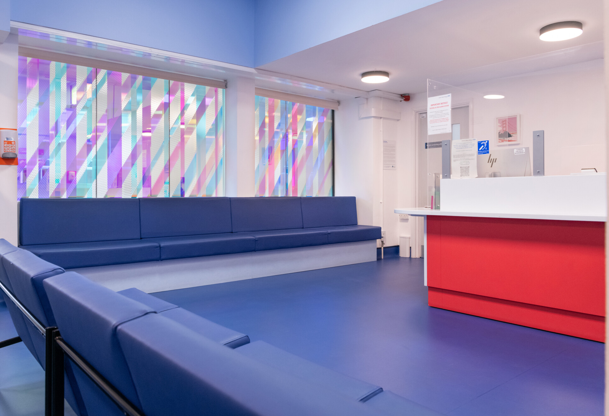 Waiting room with blue benches and rainbow glass in wall