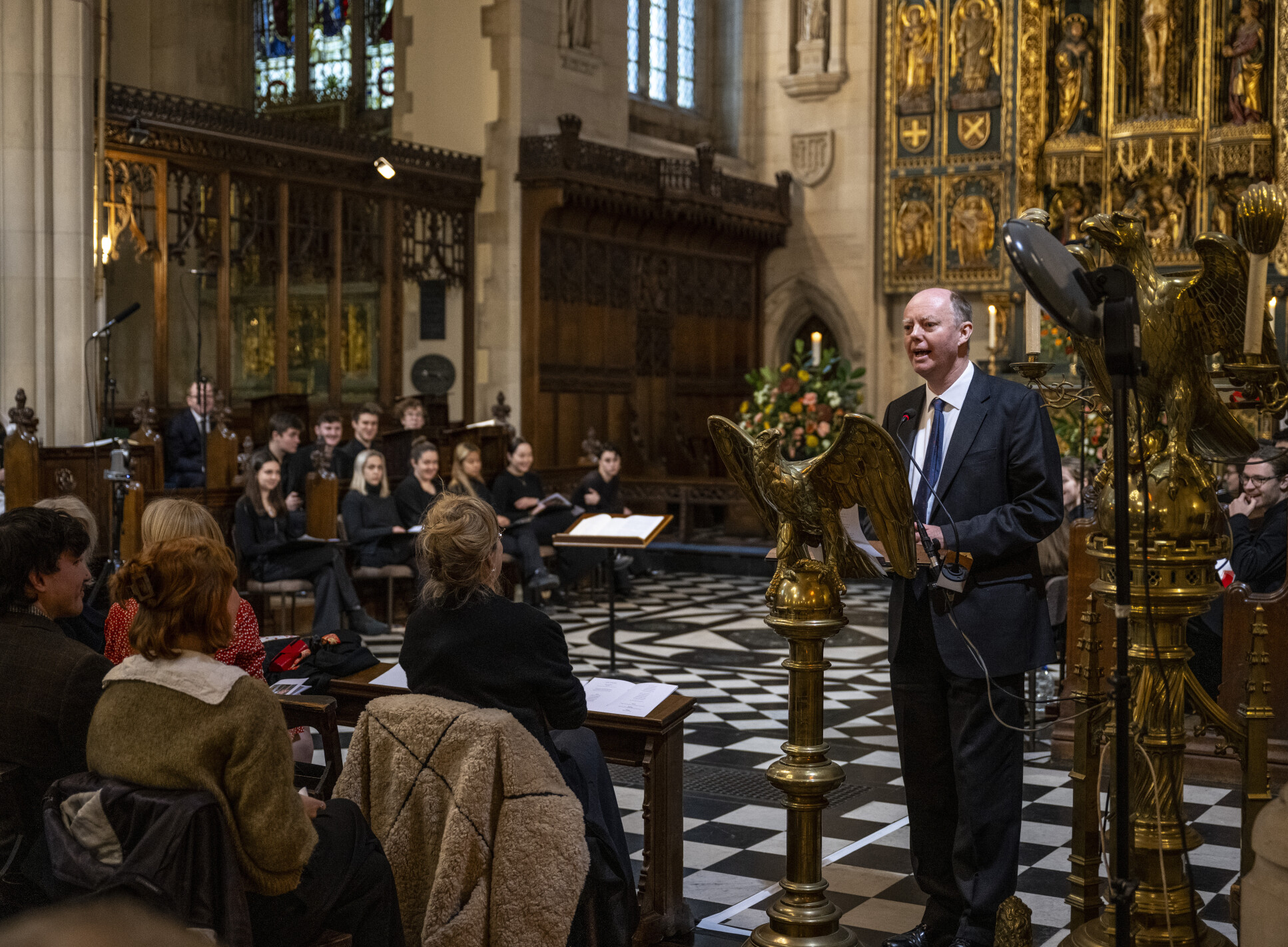 Professor Chris Whitty, standing at a podium in Holy Trinity Church, delivering a tribute.