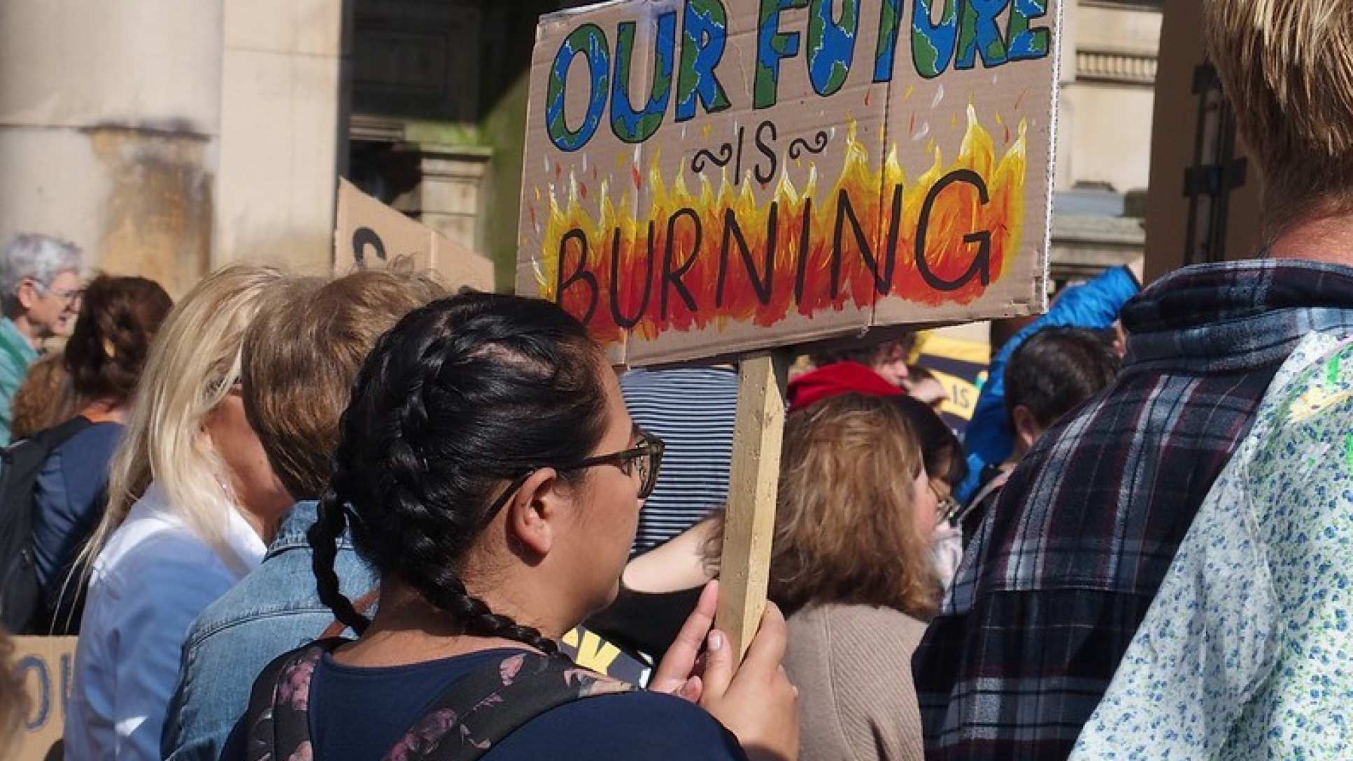 People gather at a protest, a sign reads: Our future is burning