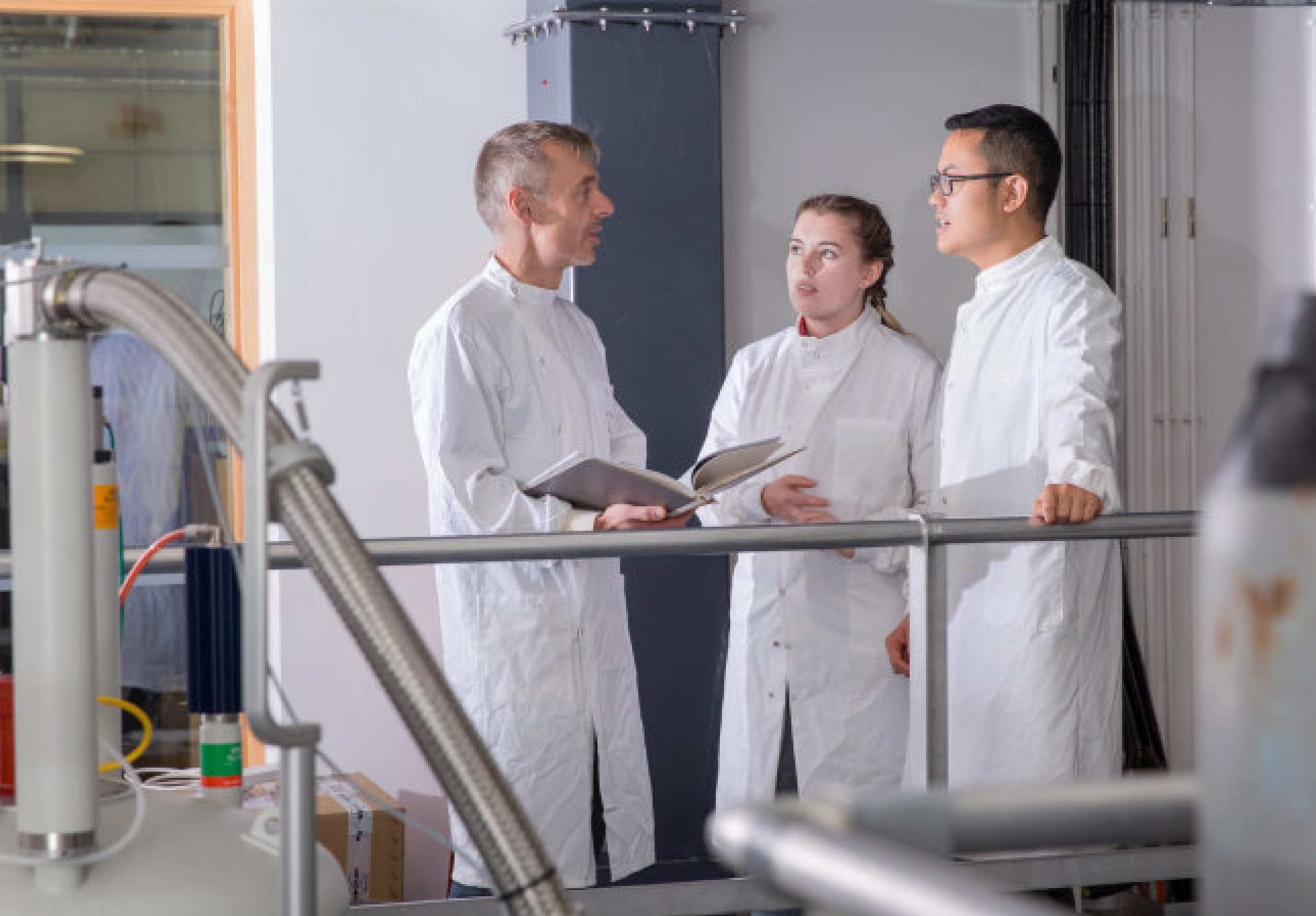 Students standing with and listening to a teacher in the lab