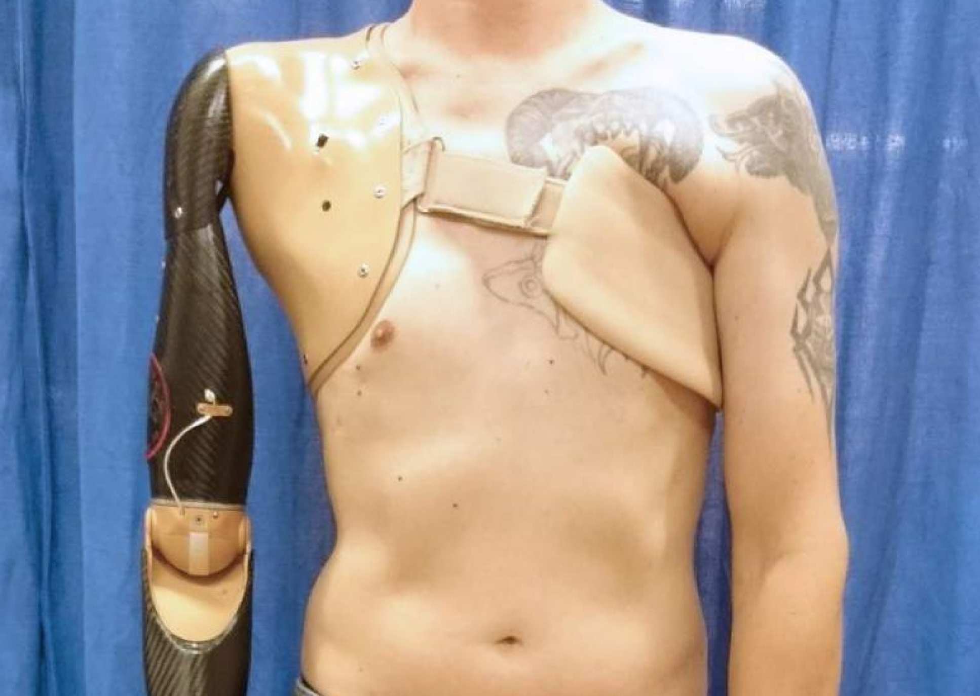 Torso of a man with a robotic arm strapped to his chest