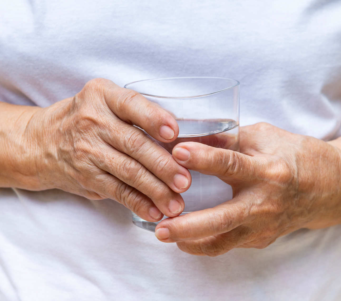Elderly person's hand holding a glass
