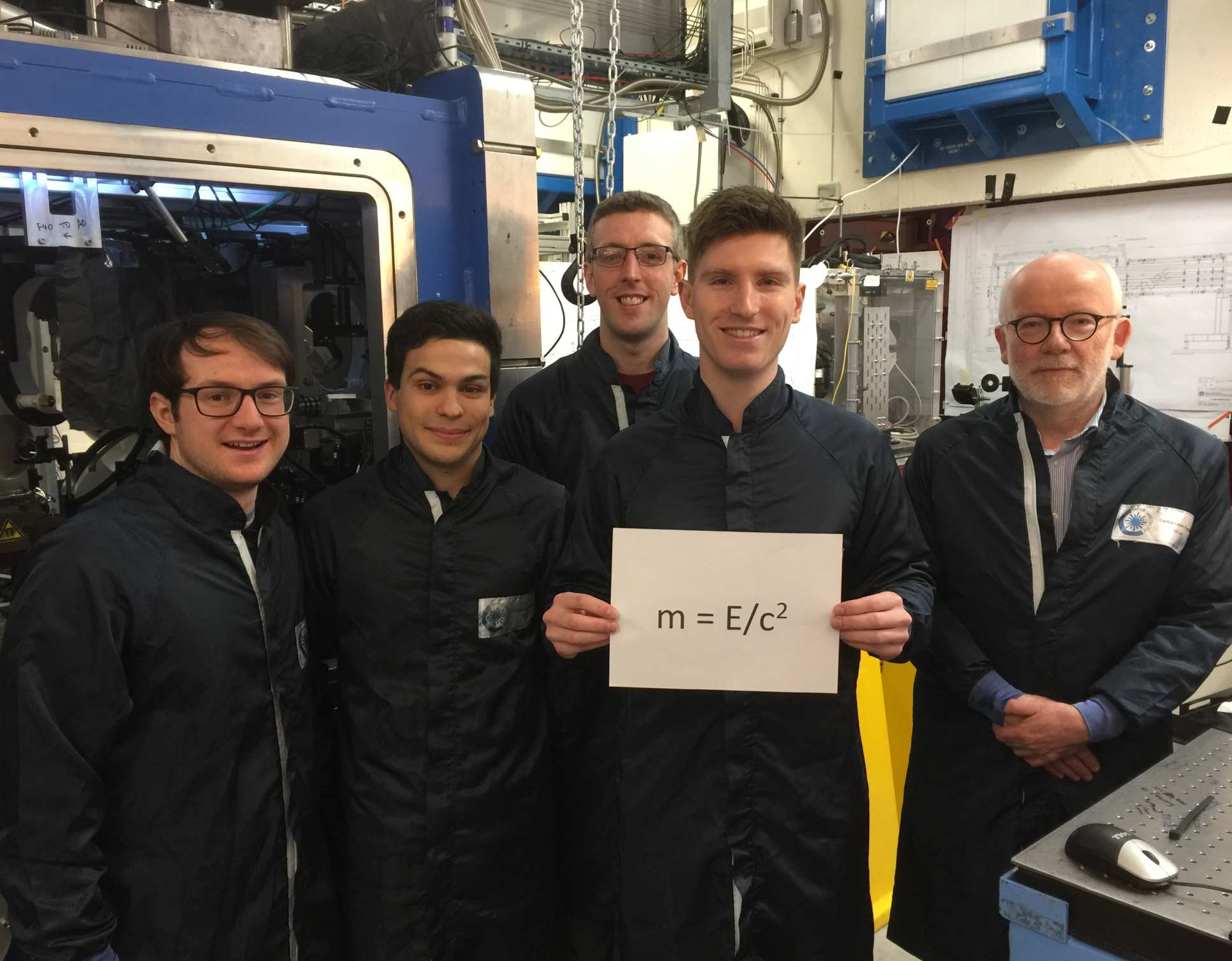 5 men in a lab holding a sign that says m=E/c2