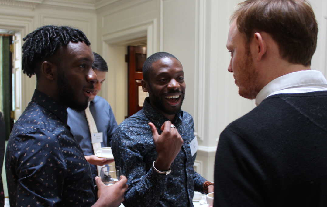 Three men converse in a group