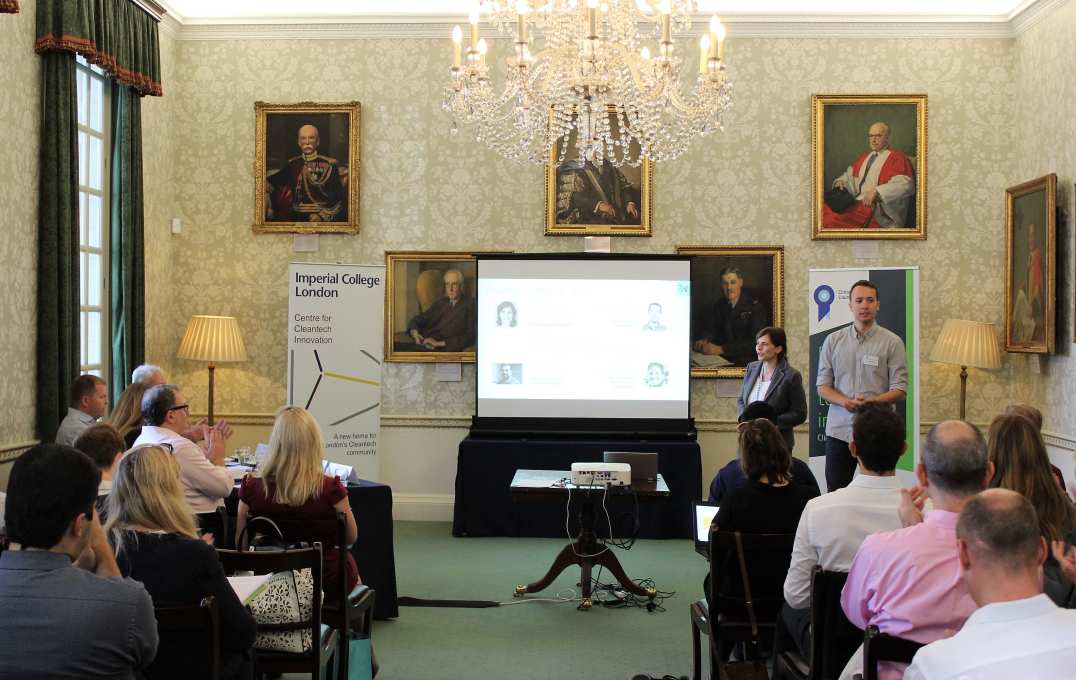 Two people stand up and present in front of a small audience