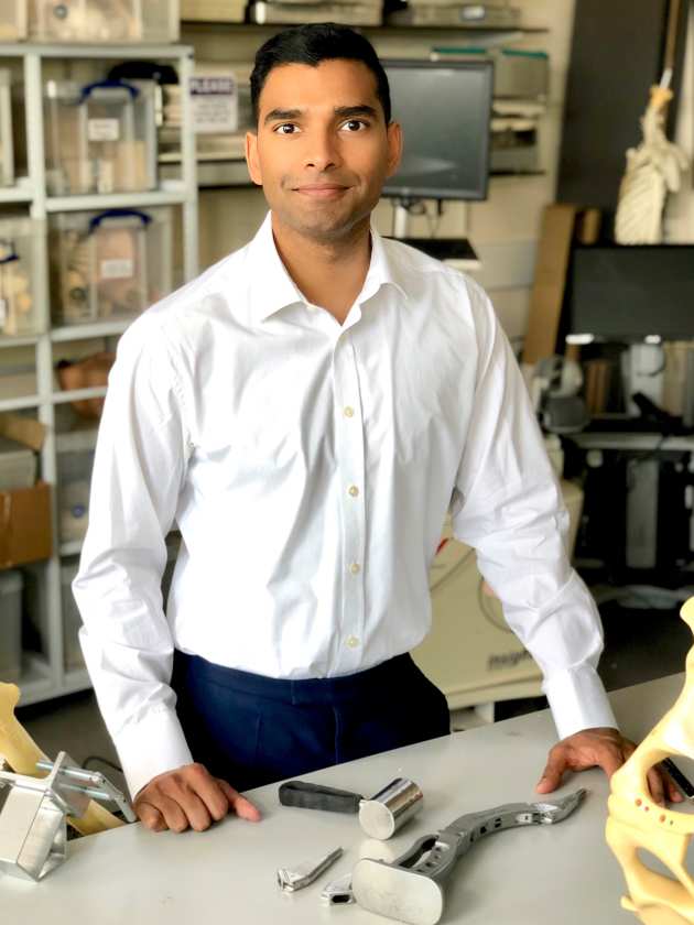 man standing in front of bench with metal pieces and tools