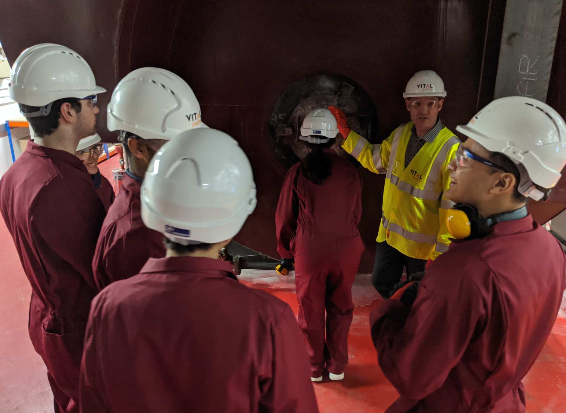 Students in the plant listening to an expert