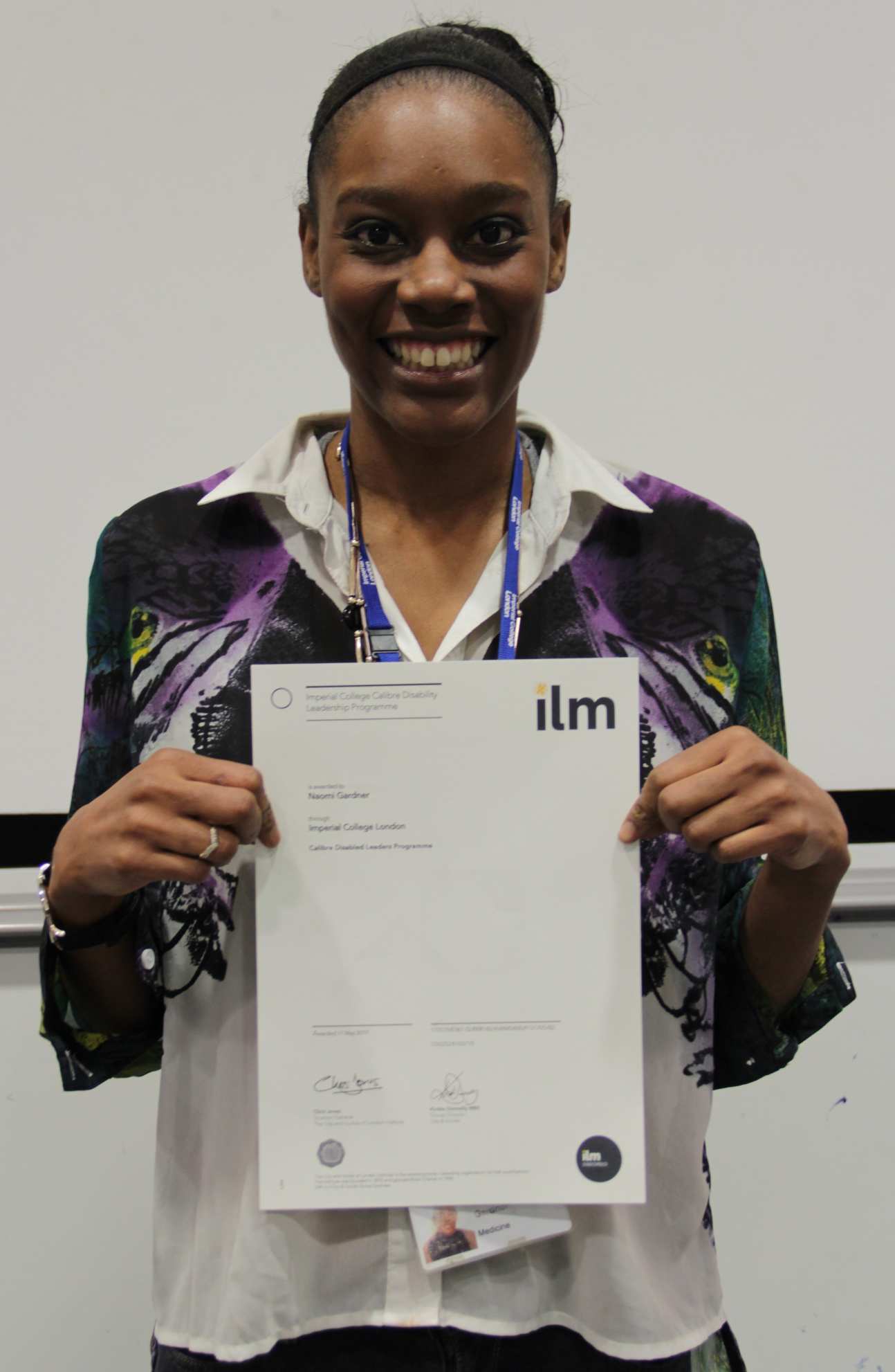 Woman smiles at camera holding certificate