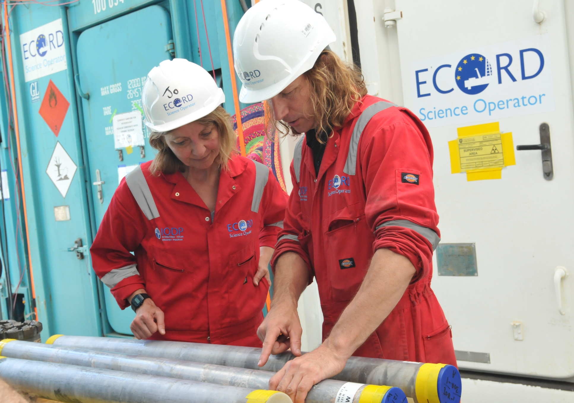 Two people look at cylinders of rock
