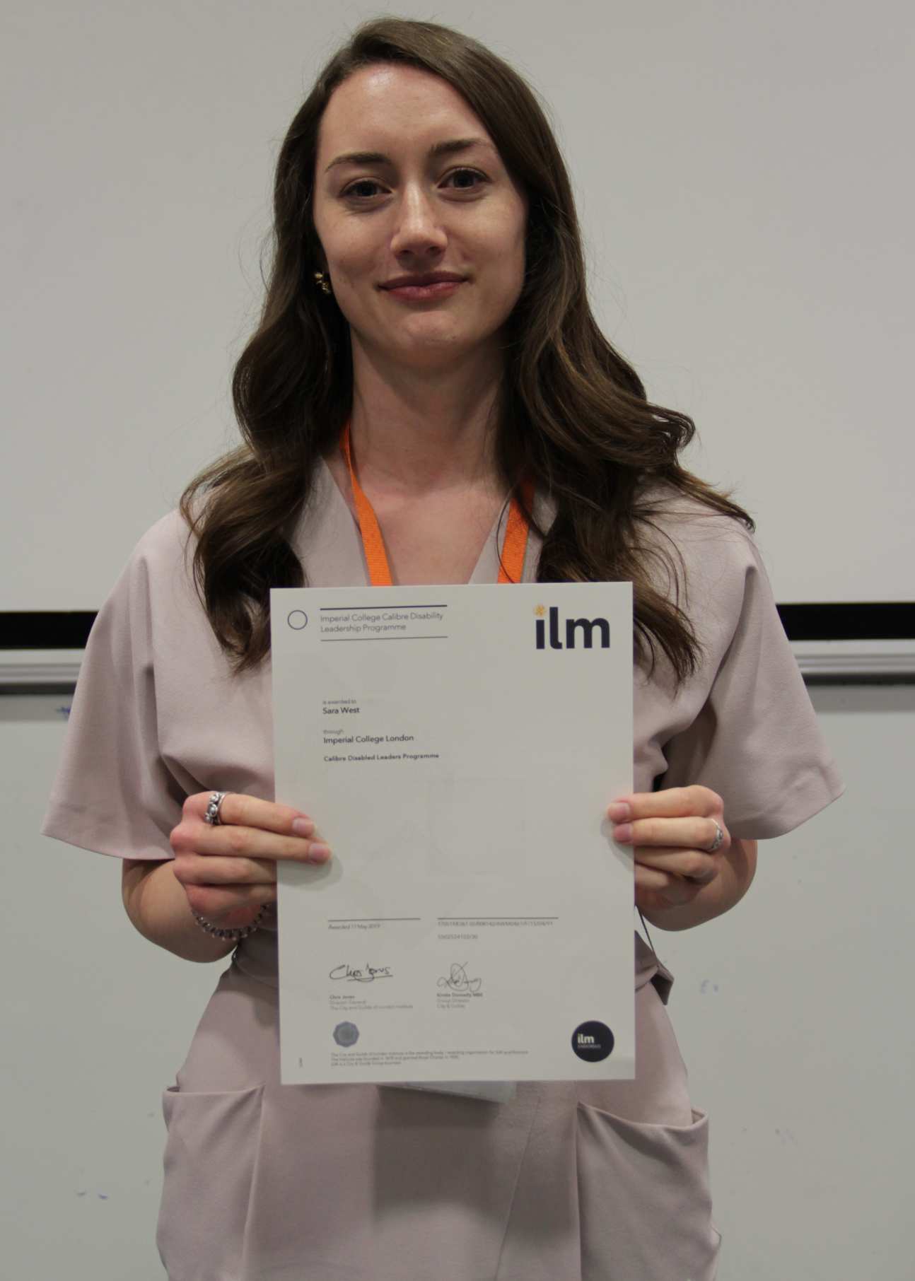 Woman smiles at camera holding certificate