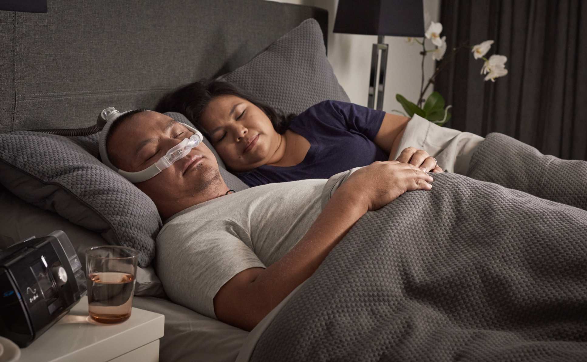 A man sleeping in bed with a CPAP machine on his face