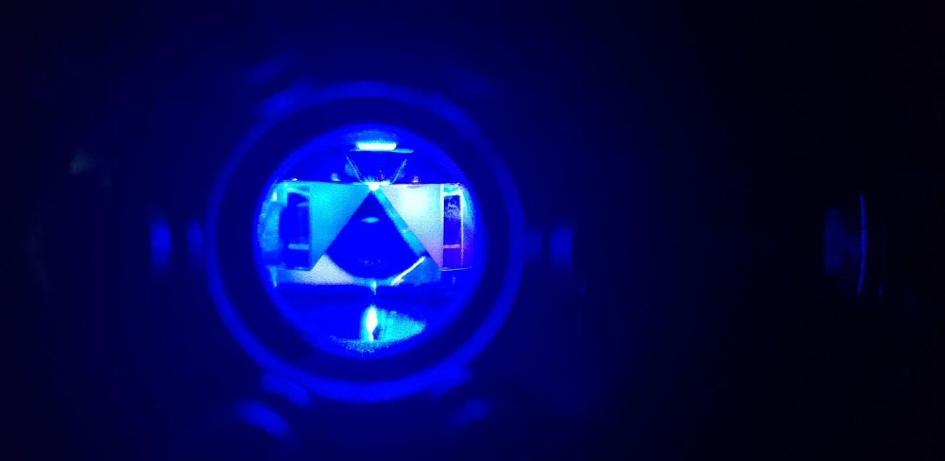 Small window into an apparatus showing a glowing blue point