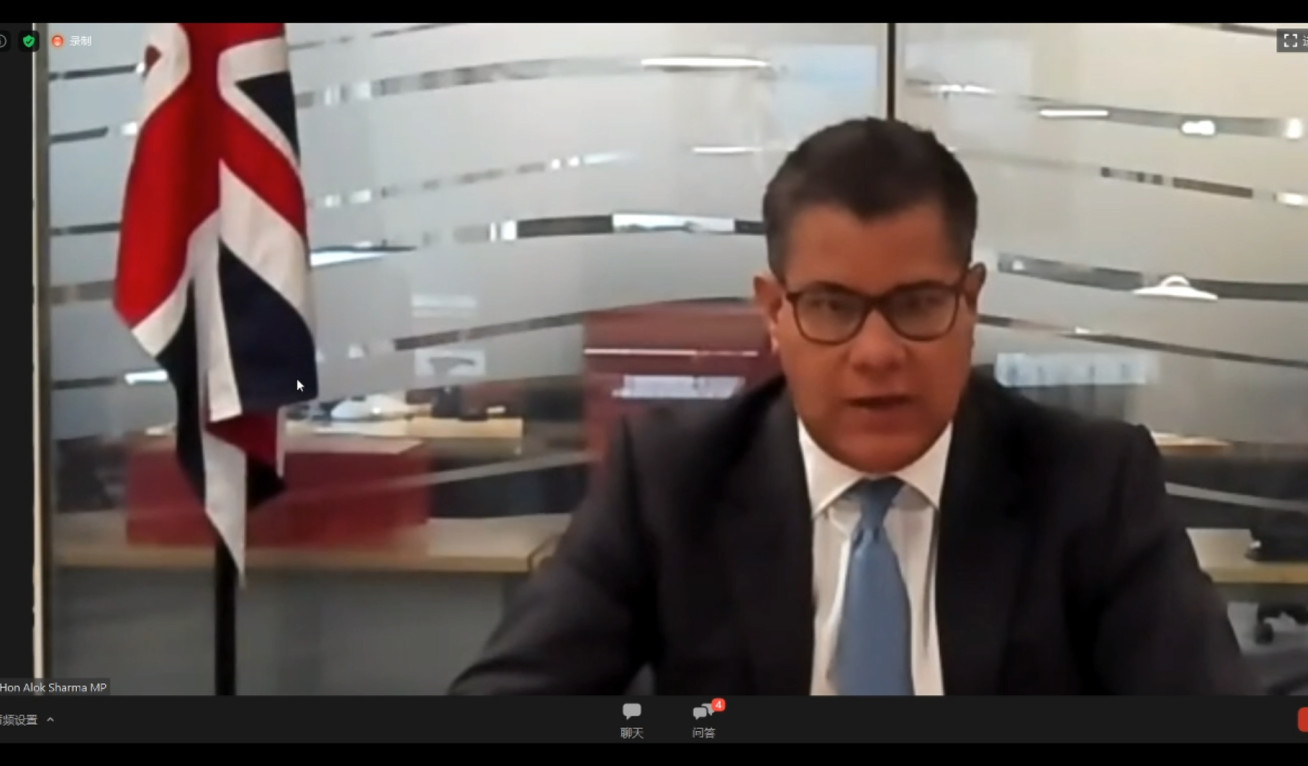 Alok Sharma viewed on a video chat screen, he sits at an office desk wearing a suit. A union flag hangs in the background.