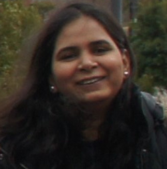 Photo shows Dr Mittal, an Indian woman with long dark hair. She is standing outside wearing a black overcoat.