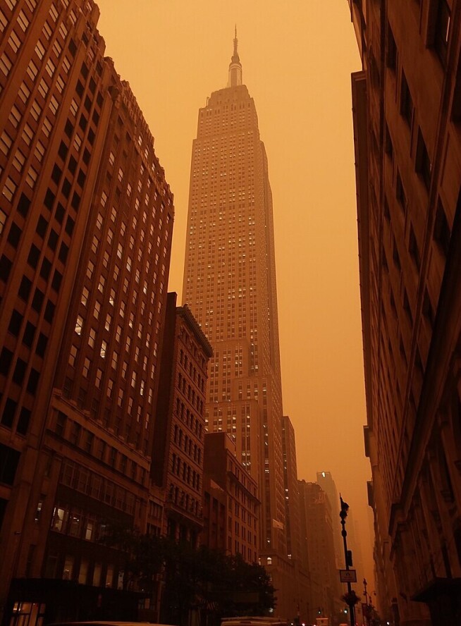 A photo of the Empire State Building in New York with hazey orange air from the wildfire smoke.