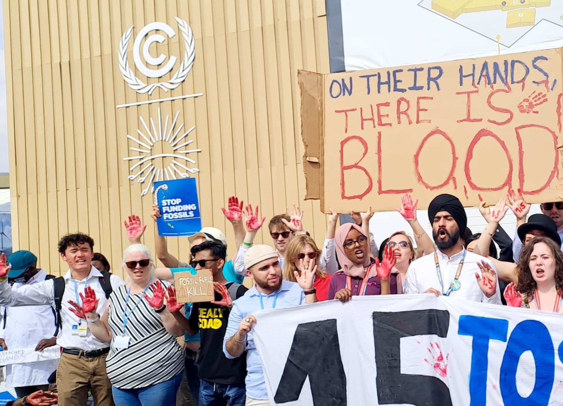 Photo of fossil fuel protest at COP27. People painted their hands red, signs read: They have blood on their hands, and Stop Fossil Fuels