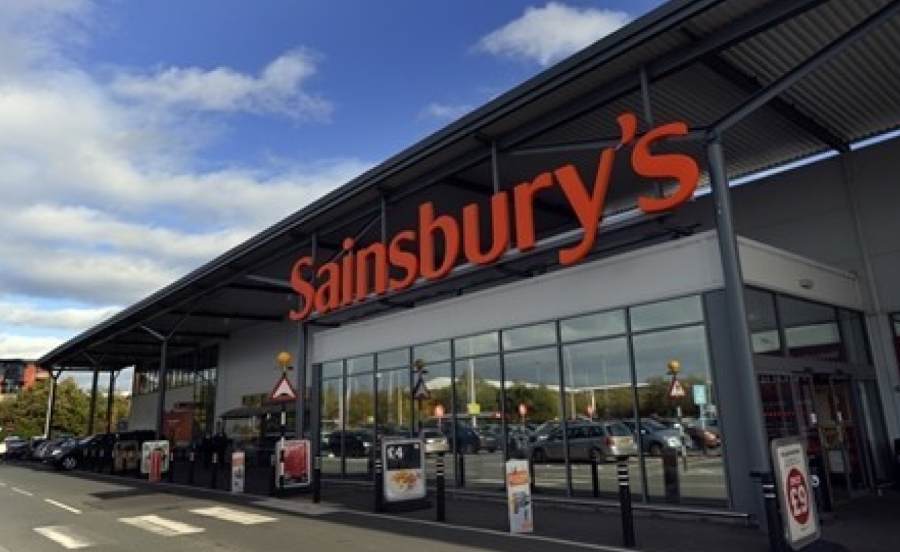 Front facade of a large supermarket with Sainsburys written above the entrance