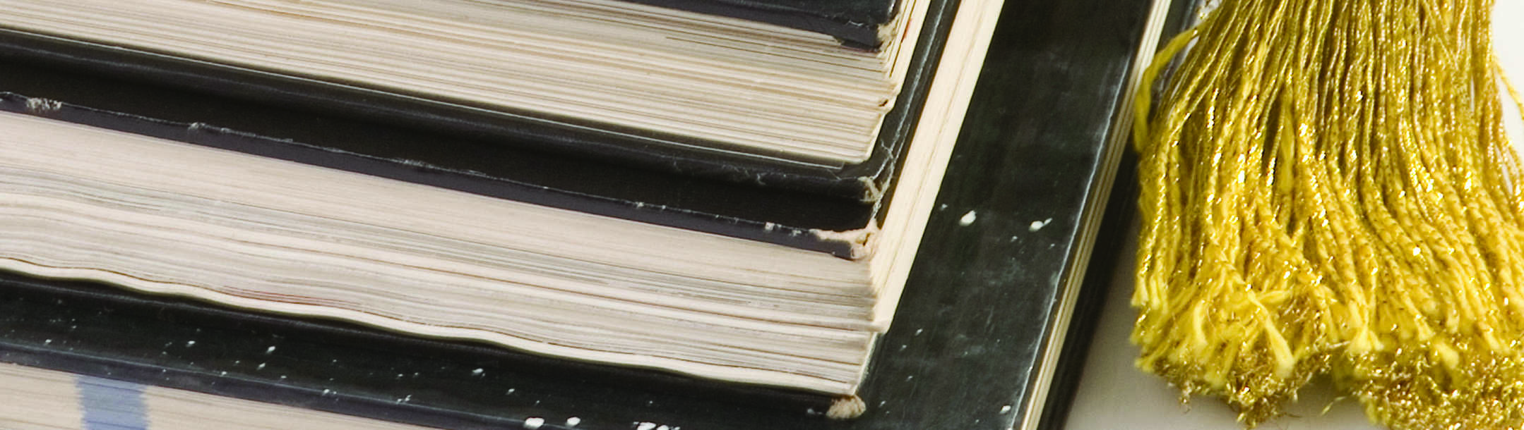 An academic cap on top of a pile of books