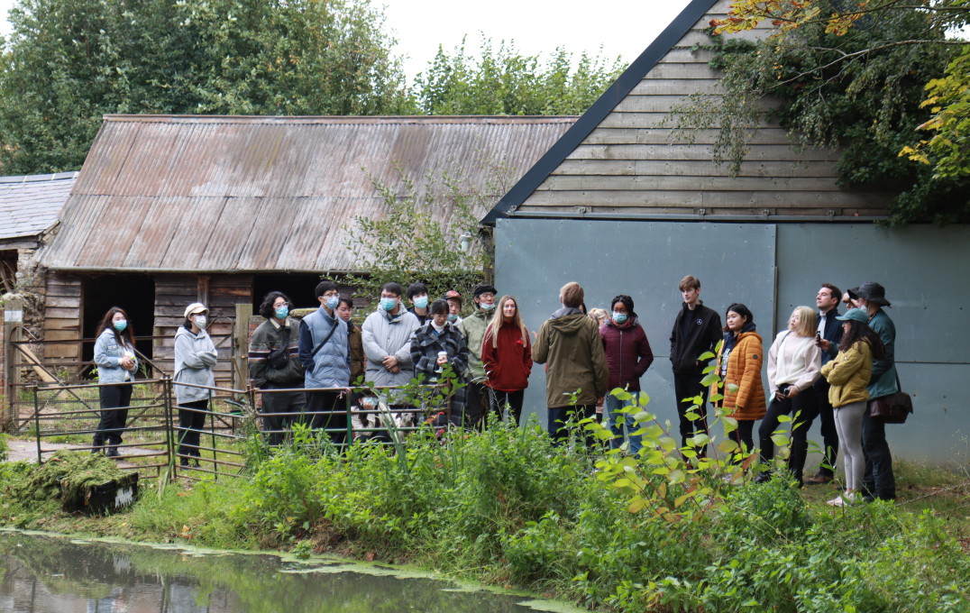 Group of students standing next to barn and pond