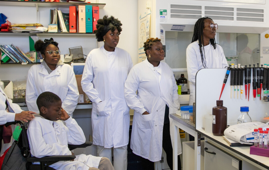 Five people in white lab coats standing in a lab