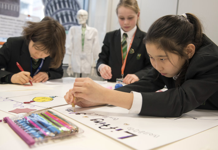 Three pupils work on a poster together
