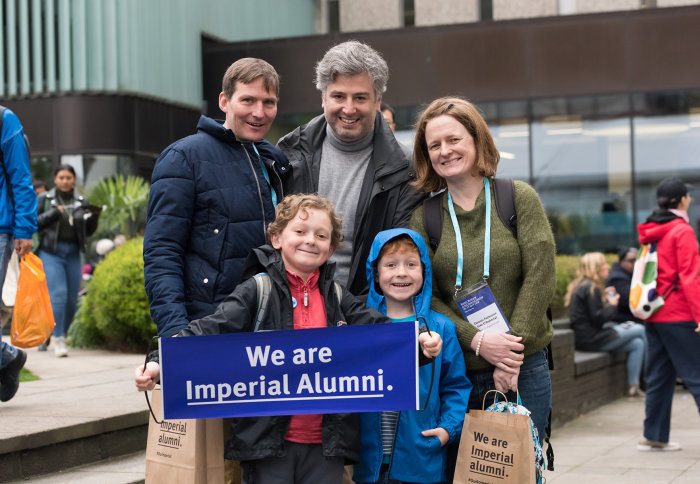 A family standing together at Alumni Weekend with an alumni banner