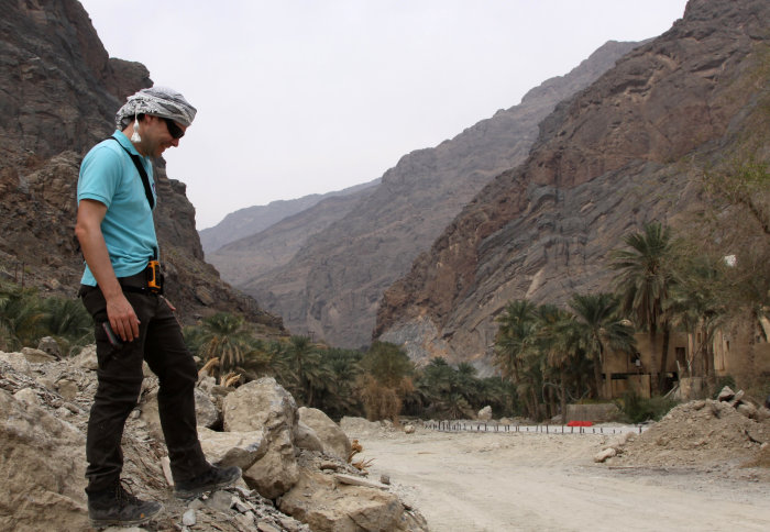 Photo of Dr Cédric John on a rock in Wadi Sahtan, Oman.