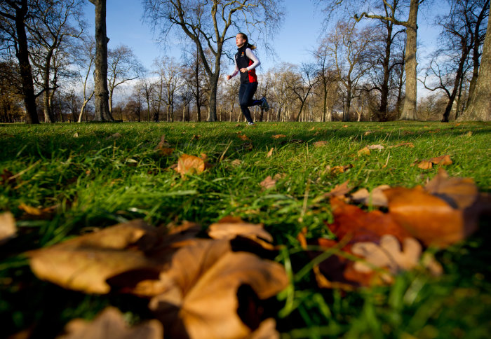 A woman running through Hyde Park on an autumn morning
