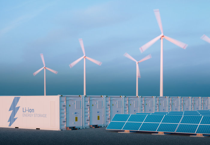 Large containers labelled 'Li-ion energy storage' in front of wind turbines and solar panels