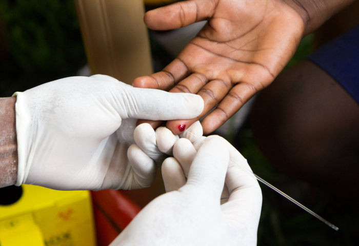 A health worker pricking a finger for an HIV test