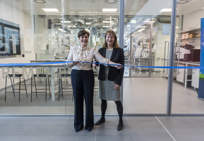 Two women cutting a ribbon in front of a lab