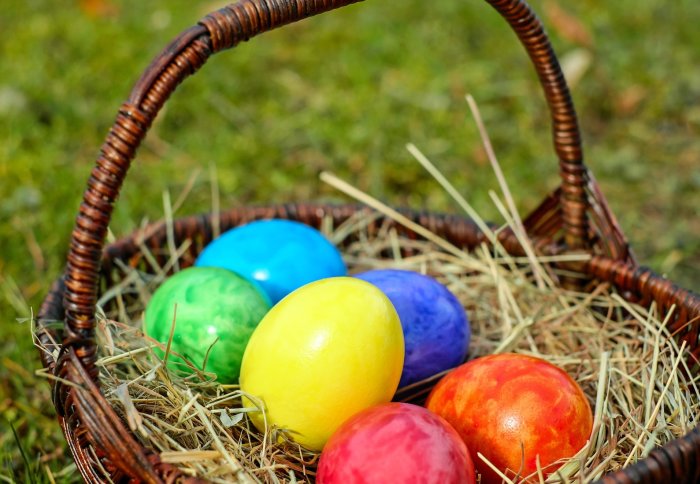 Colourful eggs in basket full of straw