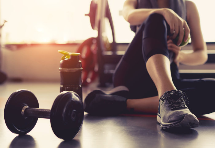 A woman sitting after a workout, surrounded by gym equipment