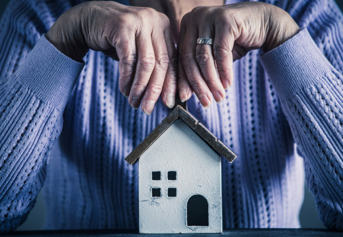 An elderly woman sitting behind a small house