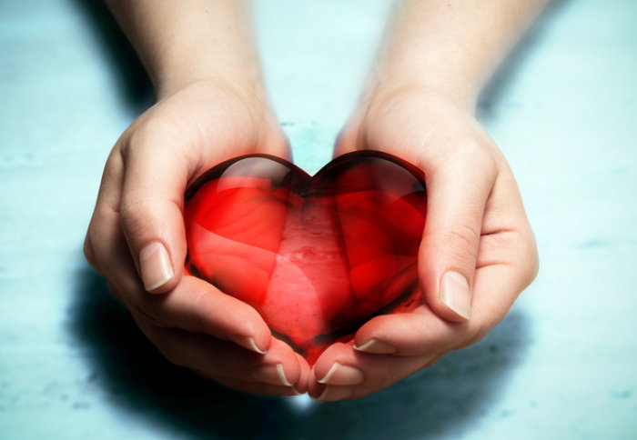 A woman's hands holding a red glass heart
