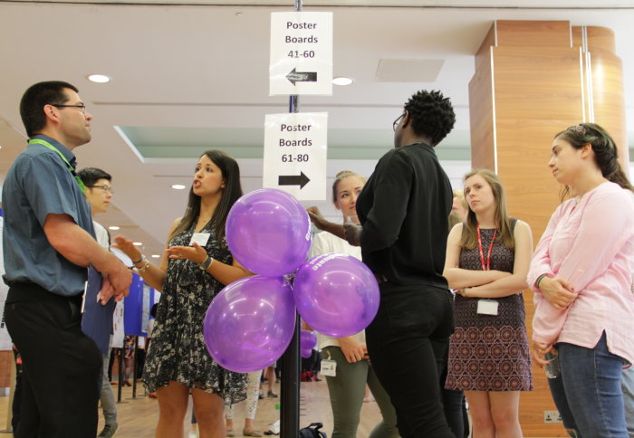 Students and staff look at poster displays