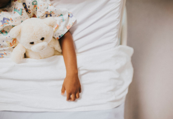 A child in bed cuddling a teddy bear