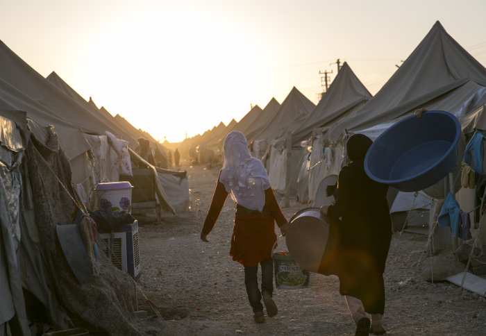 Refugee women carrying supplies in a camp