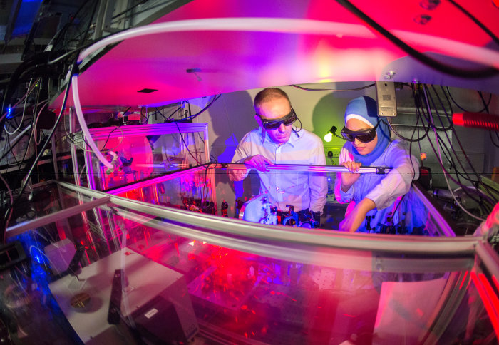 two people working on laser system, both wearing large protective dark glasses